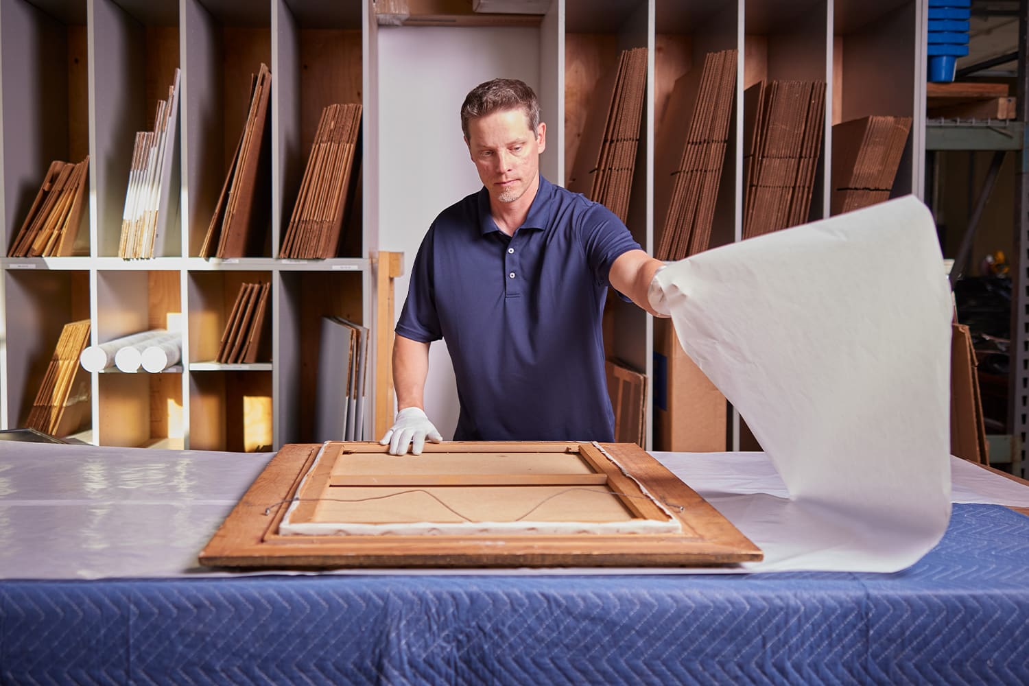 Pak Mail team member preparing framed artwork for protective packing.
