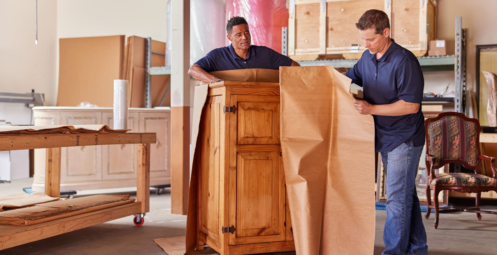 Pak Mail team members packing a large piece of furniture for shipping.