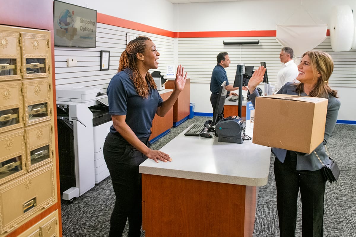Pak Mail team member assisting a customer at the shipping counter.